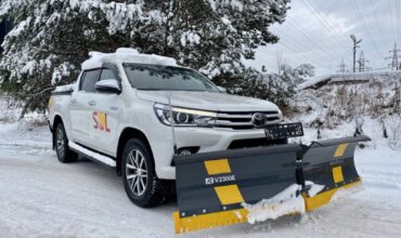 Toyota Hilux ātri nokļūst no viena objekta nākošajā objektā, šķūrē sniegu un kaisa sāli